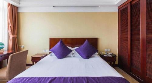 a bedroom with a large bed with purple pillows at Dajiuhua Hotel in Chizhou