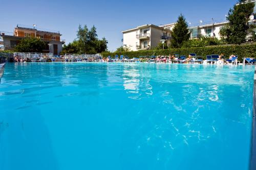 a swimming pool with blue water and people in chairs at Grand Hotel Flora in Sorrento