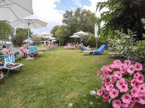 a group of people sitting on lawn chairs and umbrellas at Olive Press Hotel in Mithymna