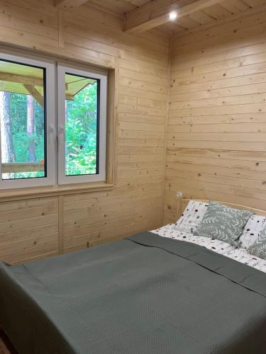 a bed in a wooden room with two windows at Leśna Oaza Radawa in Radawa