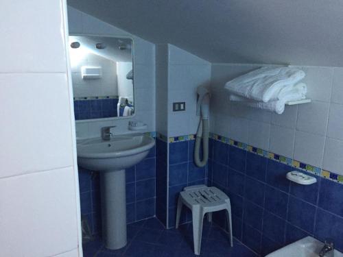 ein blau gefliestes Bad mit einem Waschbecken und einem Stuhl in der Unterkunft Hotel B&B Marina in Paestum