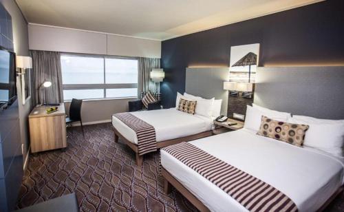 a hotel room with two beds and a television at Garden Court Marine Parade in Durban