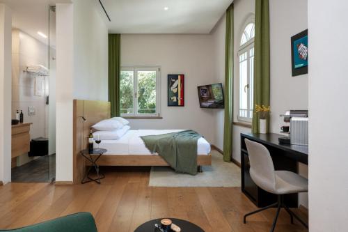 a bedroom with a bed and a desk in a room at Schumacher Hotel Haifa in Haifa