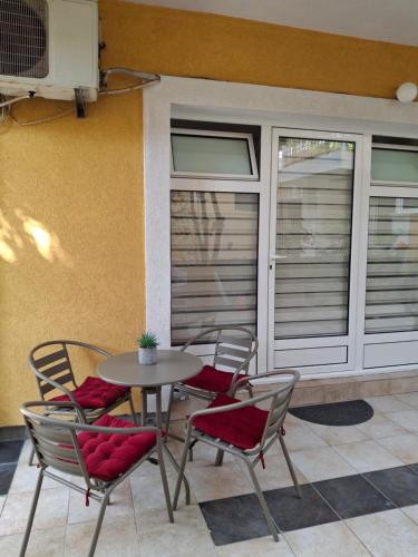 a patio with a table and chairs in front of a building at Apartmani Kojovic in Igalo