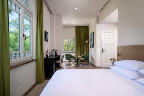 a bedroom with a bed and a desk and window at Schumacher Hotel Haifa in Haifa