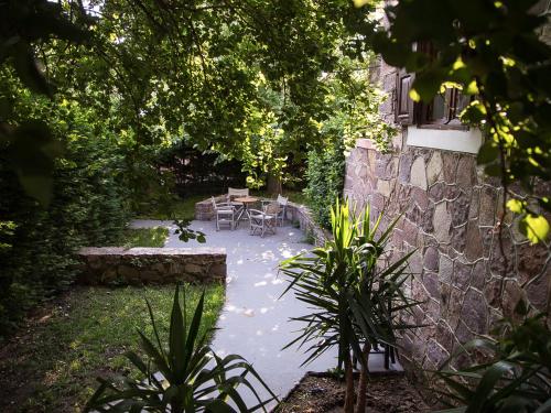 a garden with a table and chairs and a stone wall at Olive Press Hotel in Mithymna