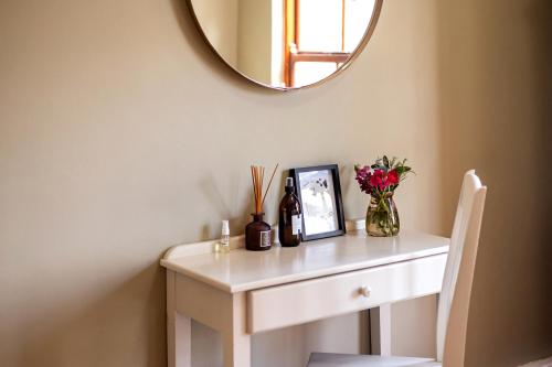 a white dressing table with a mirror and flowers on it at Leipzig Country House & Winery in Nuy