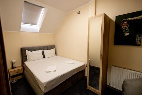 a small bedroom with a bed with a mirror at Agape Villa Apartments in Novi Sad