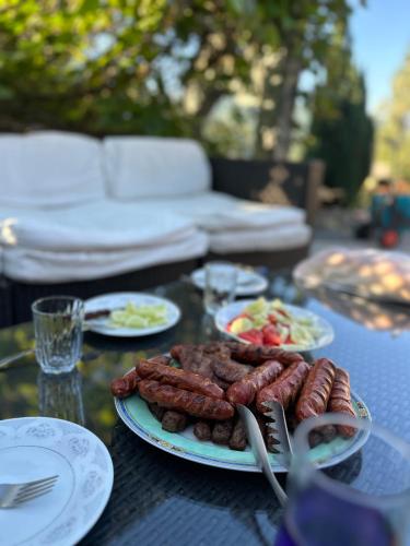 a table with plates of sausages and food on it at Vikendica Plavi Mir in Konjic