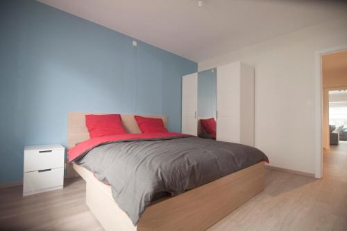 - une chambre avec un grand lit et des oreillers rouges dans l'établissement Duinenblik 3, à Nieuport