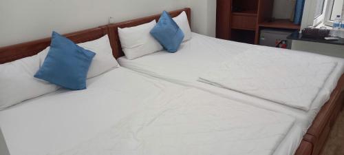 a bed with white sheets and blue pillows at Tuy Hòa Beach Hotel - Căn hộ du lịch in Tuy Hoa