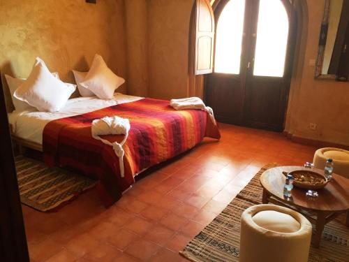 a bedroom with a bed and a table and a window at Kasbah Titrit & Spa in Aït Ben Haddou