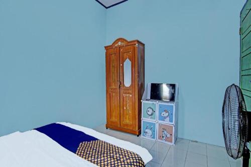 a bedroom with a bed and a wooden cabinet at SPOT ON 91918 Najla Guest House Syariah in Pekanbaru