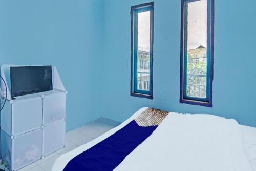 a blue bedroom with a bed and a tv at SPOT ON 91918 Najla Guest House Syariah in Pekanbaru