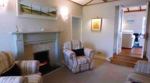a living room with two chairs and a fireplace at 1800's Cosy Cottage in Dungarvan in Balnacart