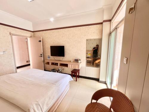 a bedroom with a white bed and a television at MAXHILL inn悦季时光酒店 in Jinghong