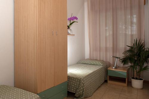 a room with a cabinet and a chair and a plant at Residence Cà D'oro in Lido di Jesolo