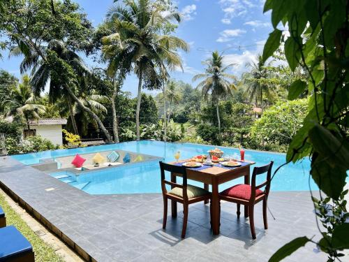 a table and chairs in front of a swimming pool at Muthu Nila villas- Mirissa in Mirissa