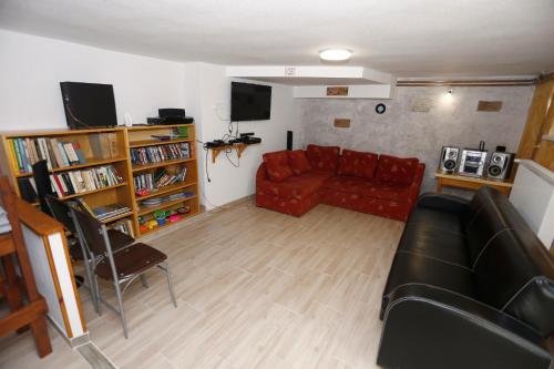 a living room with a red couch and a book shelf at Total Relax Apartmanház in Bogács