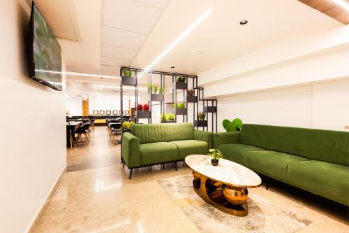 a living room with green couches and a table at Royal Plaza Inn by RAK Rooms, Calicut in Kozhikode