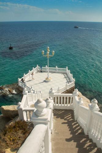 a white stairway leading to the ocean with a fountain at Irati in Benidorm