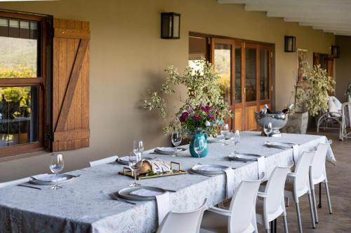 a long table with white chairs and plates and flowers at Leipzig Country House & Winery in Nuy