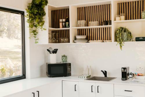 a kitchen with white cabinets and a microwave at The Ranch Cabarita Beach - Tiny Home in Clothiers Creek