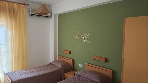 a bedroom with two beds and a green wall at Hotel La Filadelfia in Lipari