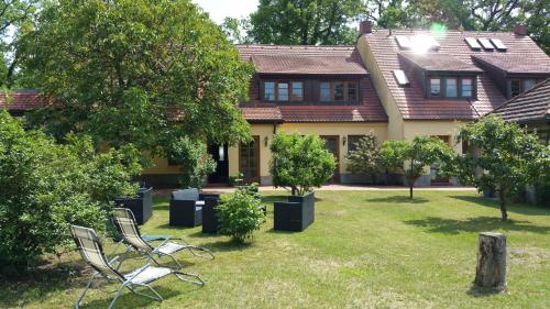 a house with two chairs and trees in the yard at Fritz Aparthotel Potsdam in Potsdam