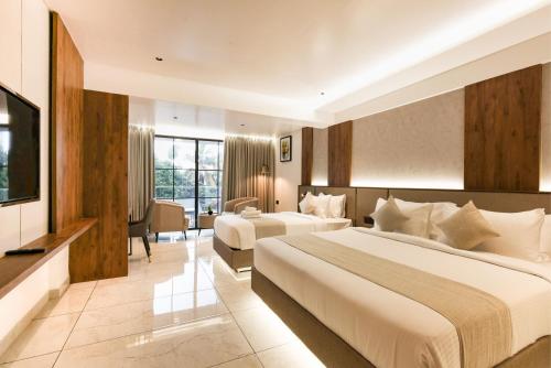 a hotel room with two beds and a television at Royal Plaza Inn by RAK Rooms, Calicut in Kozhikode