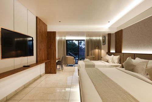 a hotel room with two beds and a flat screen tv at Royal Plaza Inn by RAK Rooms, Calicut in Kozhikode