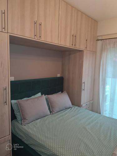 a bedroom with a bed with a green headboard and cabinets at Melodia Lefkada Apartment 3 in Nikiana