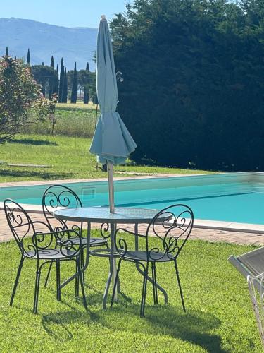 a table with an umbrella on top of it next to a pool at Affittacamere LA TENUTA in Spello