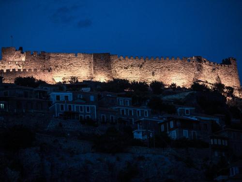 a castle sitting on top of a hill at night at Olive Press Hotel in Mithymna