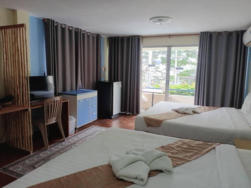 a bedroom with two beds and a desk and a television at Beachfront Hotel Cha Am in Cha Am