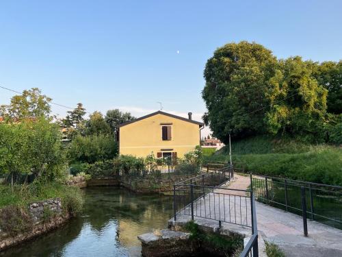 a yellow house on the side of a river at La casa ai Laghetti in Montorio Veronese