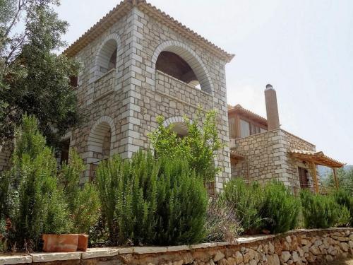 a stone house with a stone wall and some plants at Menina Farm Kalamata Countryside in Perivolákia