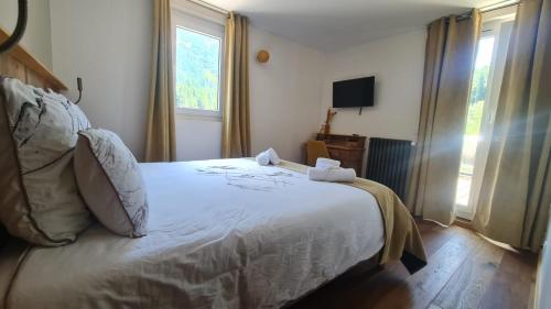 a bedroom with a bed with white sheets and a window at Domaine de Rozan - Col de Porte, Chartreuse - Grenoble in Sarcenas