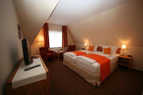 a hotel room with two beds and a television at Hotel Gutenberg in Westerland