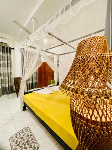 a bedroom with a yellow bed with a canopy at Nimal's House in Dickwella