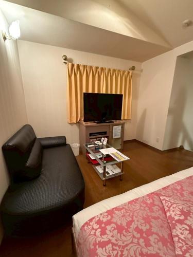 a room with a couch and a tv and a bed at HOTEL i in Takahata