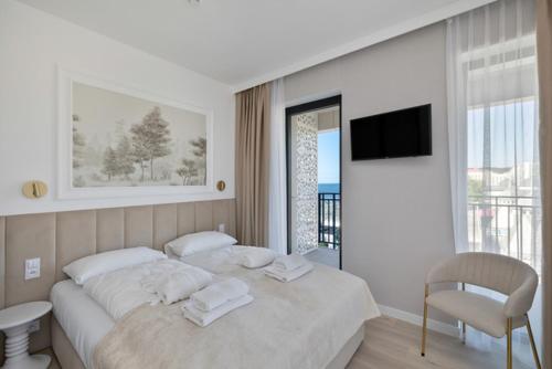 a white bedroom with a bed and a chair at Baltic View Resort&SPA Apartment 316 - Side Sea View in Międzyzdroje