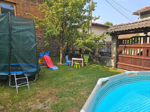 a backyard with a pool and chairs and a tree at Къща за гости Хитър Петър in Apriltsi