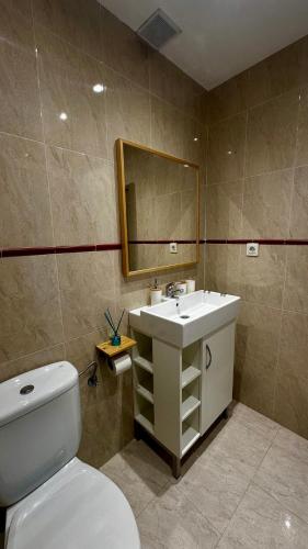 a bathroom with a toilet and a sink and a mirror at Bajo con jardines cerca de la playa in Miengo