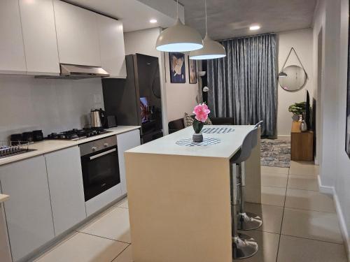 a kitchen with white cabinets and a vase of flowers on a counter at Sibaya's Luxurious Apartment in Coral Point in Umhlanga