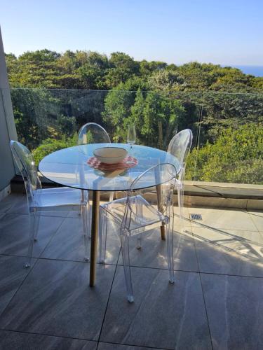 a glass table with chairs and a bowl on it at Sibaya's Luxurious Apartment in Coral Point in Umhlanga