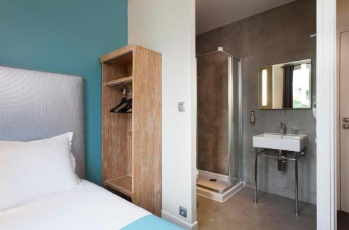 a bedroom with a bed and a sink and a shower at Hotel Douglas in Puteaux