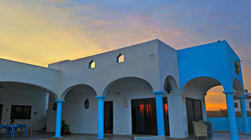 a blue and white building with a sunset in the background at Villa Star of the Sea in Barra de Navidad