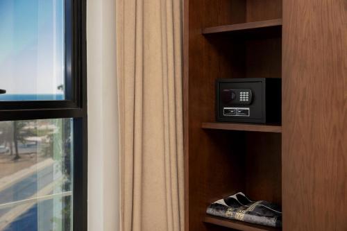 a book shelf with a tv and a window at شقق همس البحر Hams Apartments in Ḑubā