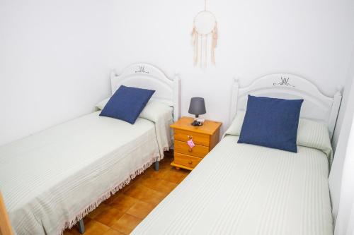 two twin beds with blue pillows in a room at Casa Luz del Carmen - Terraza, Primera Línea in Barbate